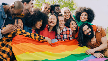 Happy diverse people holding lgbt rainbow flag outdoors - Diversity concept - Soft focus on Asian woman young woman face