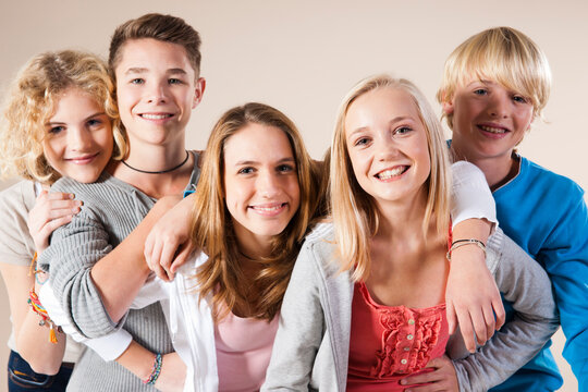 Portrait of Group of Teenage Boys and Girls Smiling at Camera, Studio Shot on White Background