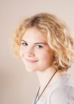 Close-up Portrait of Blond, Teenage Girl with Curly Hair, Smiling at Camera, Studio Shot on White Background