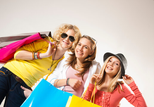 Portrait of Three, Cool Teenage Girls, Looking at Camera Smiling, Holding Shopping Bags, Diagonal Studio Shot on White Background