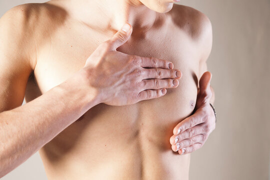 Close-up of Young Man Touching Chest in Studio