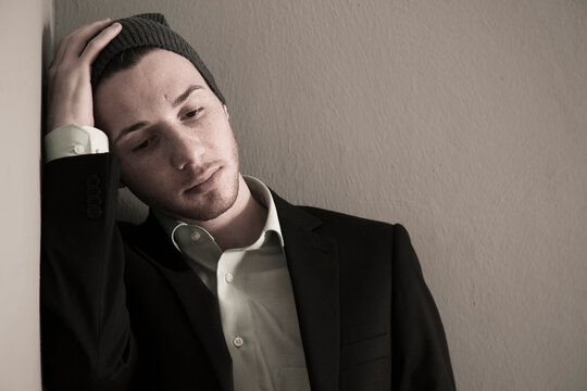 Portrait of Young Man wearing Woolen Hat and Suit Jacket, Looking Downward, Absorbed in Thought, Studio Shot