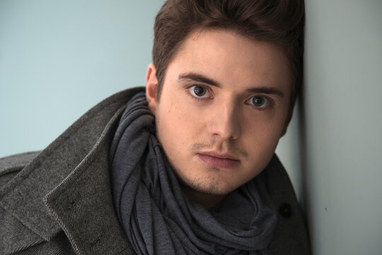 Head and Shoulder Portrait of Young Man wearing Grey Scarf and Jacket, Studio Shot on Grey Background