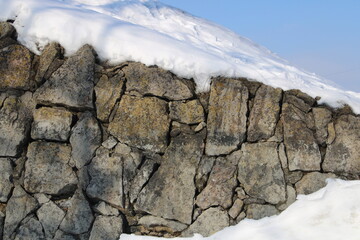 Old stone wall or rock covered by snow