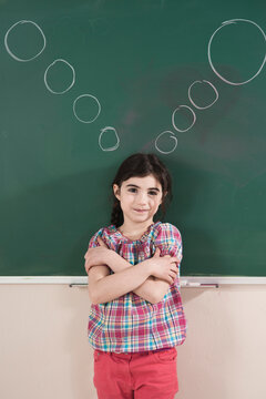 Girl in front of Chalkboard with Thought Bubbles in Classroom