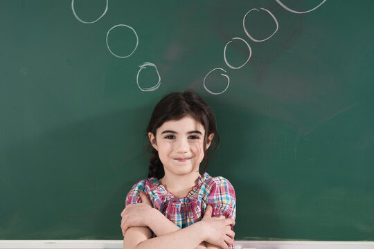 Girl in front of Chalkboard with Thought Bubbles in Classroom
