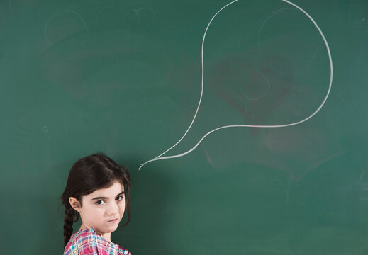Girl in front of Chalkboard with Speech Bubble in Classroom