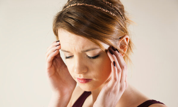 Head and shoulders portrait of teenage girl with hands on her head in studio.