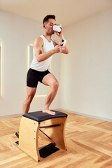 Young man drinking coffee during reformer pilates training, reformer pilates training in the gym.