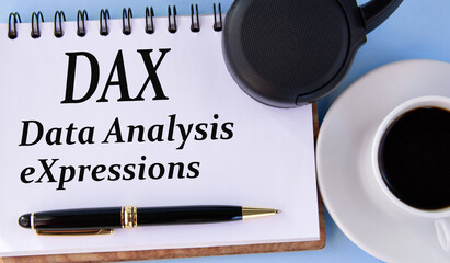 DAX (Data Analysis eXpressions) - words in a white notepad on a light background with a cup of...