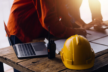 Three colleagues discussing data working and tablet, laptop with on on architectural project at construction site at desk in office