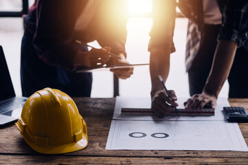 Three colleagues discussing data working and tablet, laptop with on on architectural project at construction site at desk in office