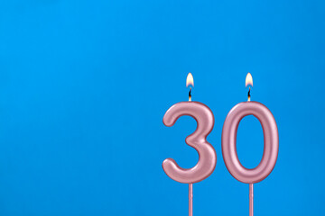 Number 30 - Burning anniversary candle on blue foamy background