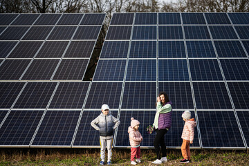 Mother with three kids on the background of solar panels.  Eco energy.