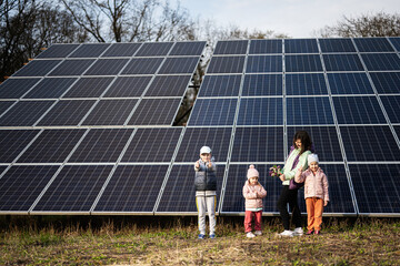 Mother with three kids on the background of solar panels.  Eco energy.