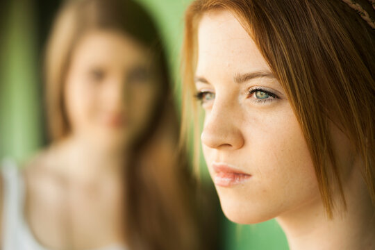 Sideview portrait of teenage girl with young woman in background