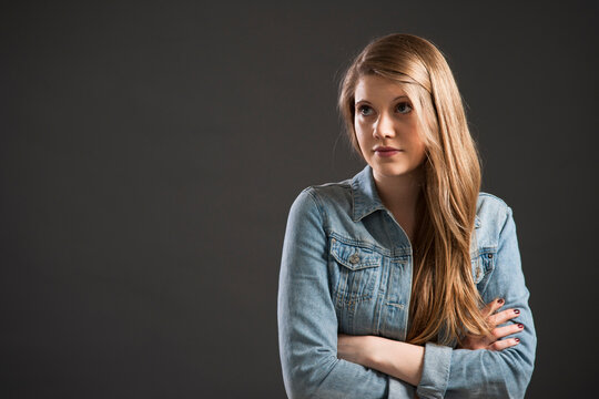 Portrait of young woman with long, blond hair, studio shot on grey background