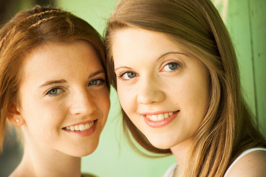 Close-up portrait of young women outdoors, smiling at camera