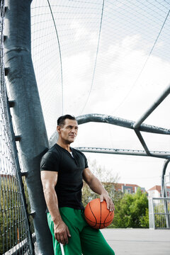 Portrait of mature man standing on outdoor outdoor basketball court, Germany