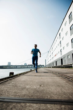 Mature man running along loading dock in front of warehouse, Mannheim, Germany