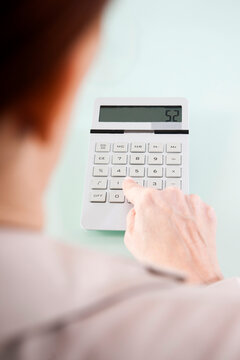 Over the Shoulder View of Mature Woman using Calculator in Office