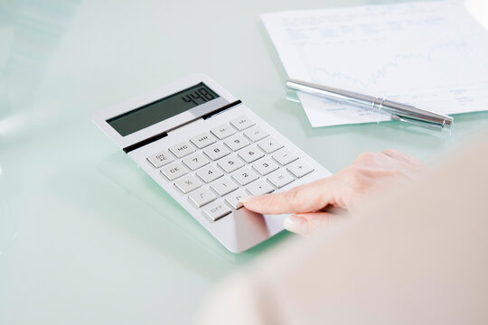 Close-up of Mature Woman's Hand using Calculator in Office