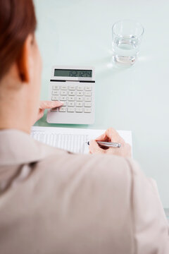 Over the Shoulder View of Mature Woman Working on Budget in Office