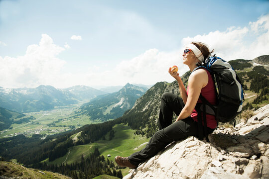 Mature woman sitting on cliff, hiking in mountains, Tannheim Valley, Austria