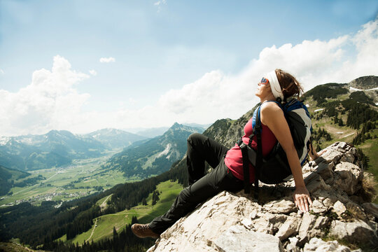 Mature woman sitting on cliff, hiking in mountains, Tannheim Valley, Austria