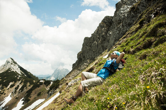 Mature woman lying on grass, hiking in mountains, Tannheim Valley, Austria