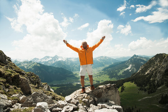 Mature man with arms raised in air, hiking in mountains, Tannheim Valley, Austria
