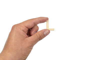 A hand holding a wooden letter l in front of a white background