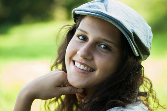 Close-up portrait of teenaged girl wearing cap outdoors, smiling and looking at camera, Germany