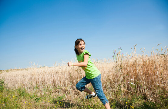 Girl running in field on hill, Germany