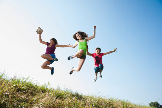 Girls jumping in mid-air over field, Germany