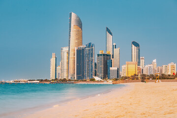 Panoramic view of stunning sandy beach near Corniche seaside embankment with great sunset view of Abu Dhabi, UAE towering skyscrapers