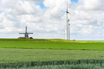 Wind turbines for electricity generation next to an old windmill in tha countryside of Netherlands...