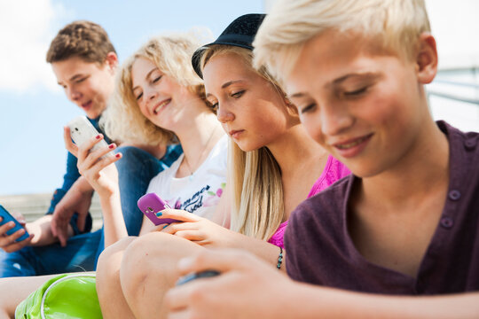Teenagers using Cell Phones Outdoors, Mannheim, Baden-Wurttemberg, Germany