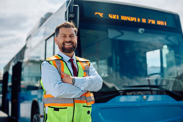 Happy bus driver standing with arms crossed at looking at camera.