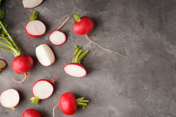 Fresh red radishes slice with leaves on grey background, space for text, flat lay.