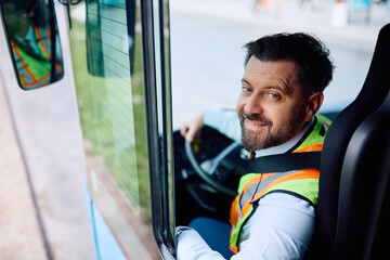 Happy bus driver in vehicle cabin looking at camera.