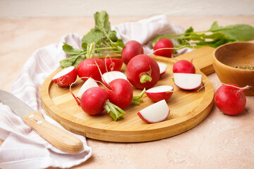 Fresh red radish on cutting board on beige background.