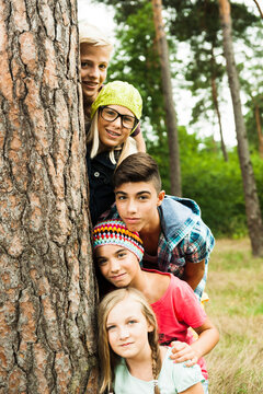 Portrait of group of children posing next to tree in park, Germany