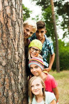 Portrait of group of children posing next to tree in park, Germany