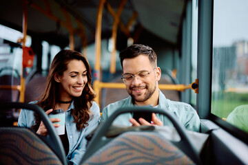Happy couple using mobile phone while riding in bus.