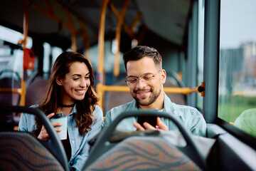 Happy couple using mobile phone while riding in bus. © Drazen