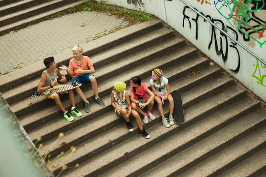 Overhead view of group of children sitting on stairs outdoors, Germany