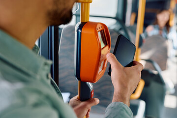 Close up of man using mobile phone while paying for bus fare.