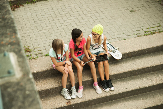 Girls Sitting on Steps with Tablet Computers and Skateboard, Mannheim, Baden-Wurttemberg, Germany