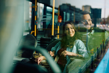 Young happy couple looking through window while riding in bus.